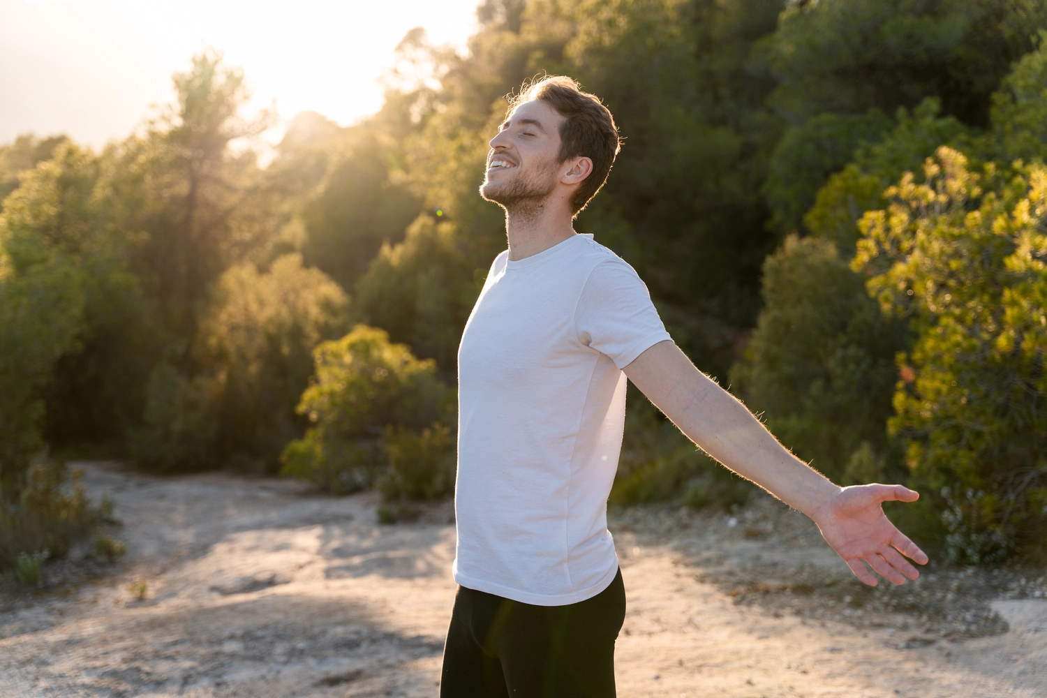 HeilOase - heile von innen - Ein attraktiver Mann atmet bei Sonnenuntergang die frische Luft der Natur ein.